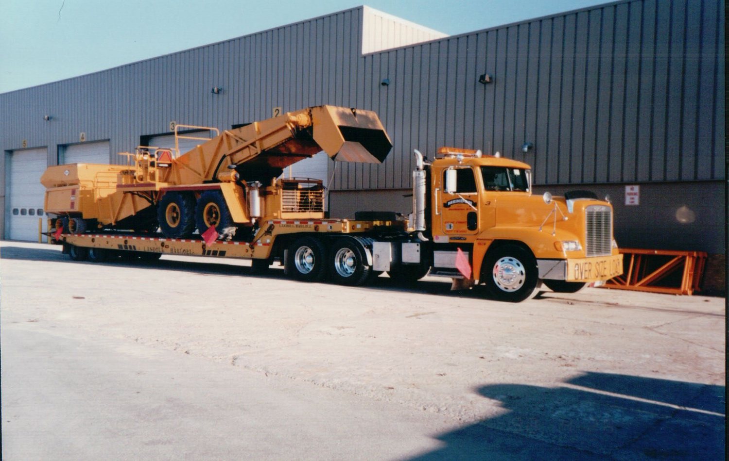 Truck hauling a yellow scraper, oversize load