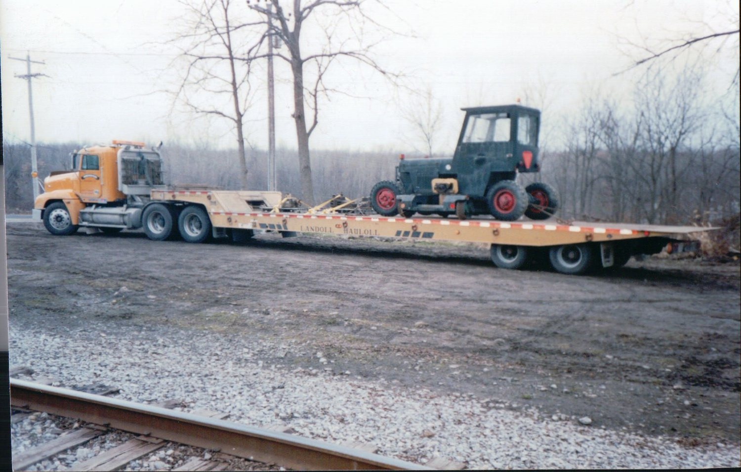 Mack truck hauling a vintage tractor on a Landoll trailer